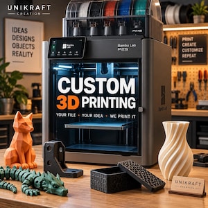 Pode incluir: Uma impressora 3D Bambu Lab P2S com uma unidade AMS no topo, exibindo o texto CUSTOM 3D PRINTING YOUR FILE YOUR IDEA WE PRINT IT. Na mesa estão uma raposa geométrica laranja, um dragão articulado verde, uma caixa preta e um vaso branco.