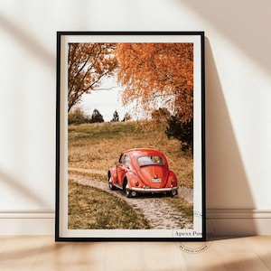 May include: A framed vertical wall art print featuring a bright red vintage Volkswagen Beetle parked on a gravel path. The scene is set in a landscape with golden autumn trees and dry grass. The text Apexx Posters No Copies Allowed is visible.