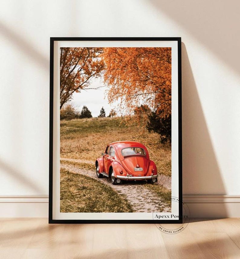 May include: A framed vertical wall art print featuring a bright red vintage Volkswagen Beetle parked on a gravel path. The scene is set in a landscape with golden autumn trees and dry grass. The text Apexx Posters No Copies Allowed is visible.