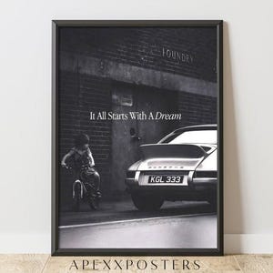 May include: A black and white framed wall art print featuring a child on a bicycle next to a parked sports car in front of a brick building. The text It All Starts With A Dream is centered above the car, and the license plate reads KGL 333.