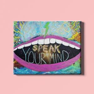 May include: A colorful canvas art piece featuring a large, stylized mouth with bright pink lips and white teeth. The words "SPEAK YOUR MIND" are written inside the mouth. A green lightning bolt is above the mouth.