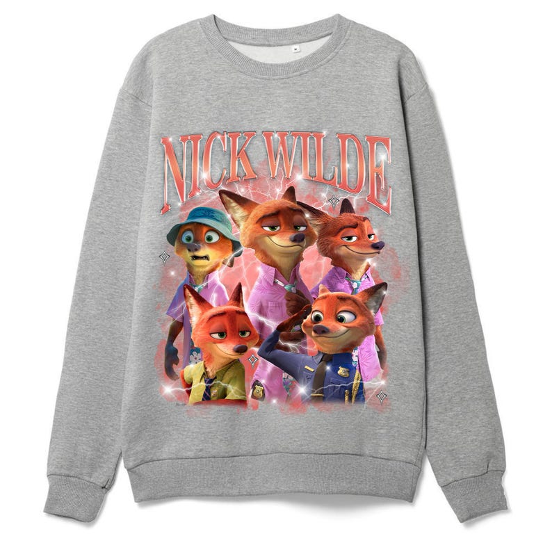 K&ouml;nnte beinhalten: Ein graues Sweatshirt mit einer Grafik der Figur Nick Wilde aus dem Animationsfilm Zoomania. Die Grafik enth&auml;lt den Text "NICK WILDE" in einer Retro-Schriftart sowie Bilder der Figur und anderer Charaktere.