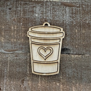 May include: A wooden cutout of a coffee cup with a heart on the front. The cup is brown and the heart is white.