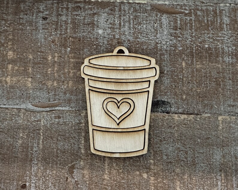 May include: A wooden cutout of a coffee cup with a heart on the front. The cup is brown and the heart is white.