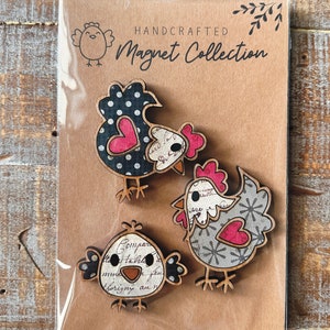 Puede incluir: Conjunto de tres imanes de pollo de madera hechos a mano. Los pollos est&aacute;n decorados con lunares negros y blancos, copos de nieve grises y blancos y un patr&oacute;n floral vintage. Cada pollo tiene un coraz&oacute;n rosa en el pecho. Los imanes est&aacute;n empaquetados en una tarjeta marr&oacute;n con el texto "HANDCRAFTED Magnet Collection".