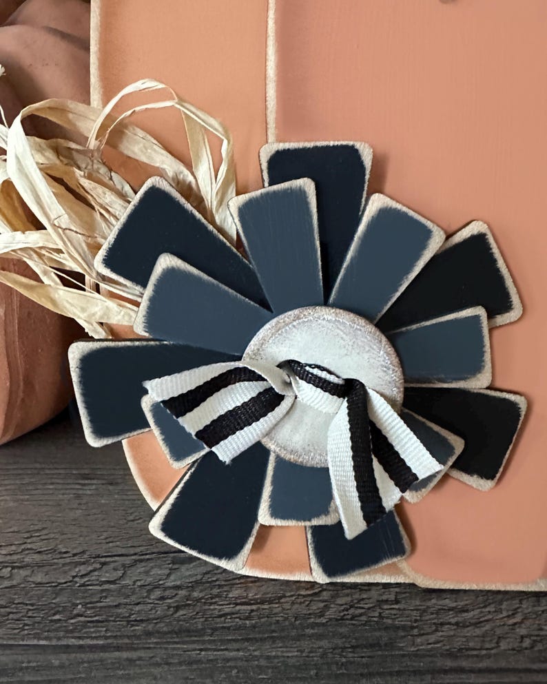 Pode incluir: Uma flor de madeira preta e branca com um la&ccedil;o branco e preto listrado no centro. A flor &eacute; feita de v&aacute;rias pe&ccedil;as de madeira pintadas de preto e branco.
