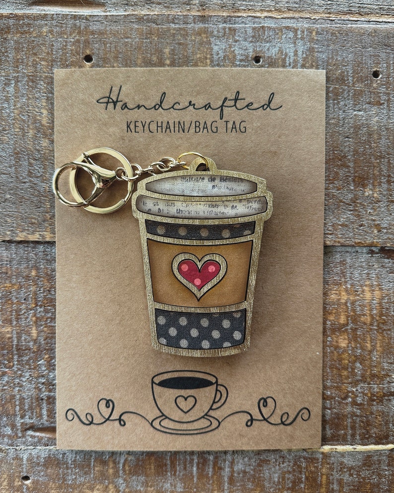 May include: Handcrafted wooden keychain or bag tag shaped like a coffee cup with a red heart and polka dots. The tag is attached to a gold metal key ring.