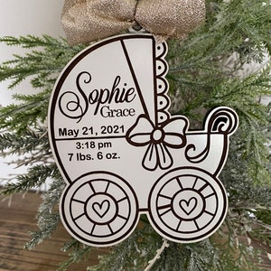 May include: White wooden baby carriage ornament with the name "Sophie Grace" and the date "May 21, 2021" and the time "3:18 pm" and the weight "7 lbs. 6 oz."
