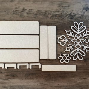 Puede incluir: Un conjunto de cinco piezas de madera sin terminar para manualidades. Las piezas incluyen cuatro formas rectangulares y un dise&ntilde;o de copo de nieve. Las piezas son perfectas para pintar, te&ntilde;ir o decoupage.