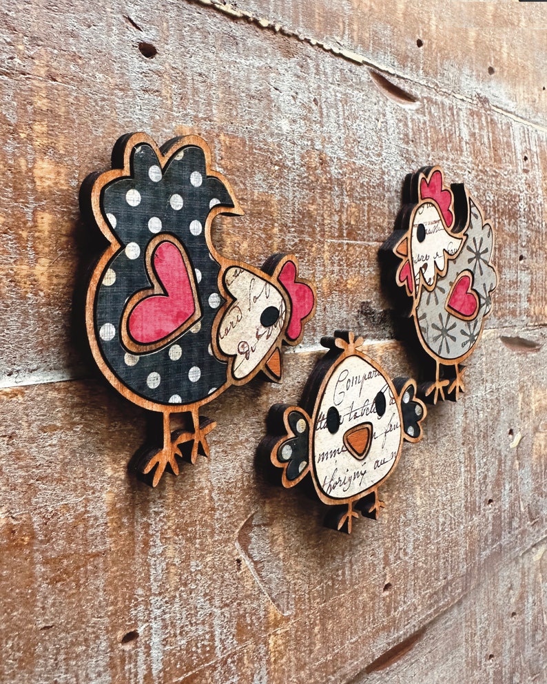 Puede incluir: Tres adornos de pollo de madera con patrones de lunares negros y blancos, corazones rojos y texto de estilo vintage. Los pollos est&aacute;n en varias poses, incluyendo de pie, sentados y mirando hacia un lado.