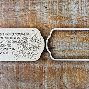 May include: Two wooden plaques with a floral design and text. One plaque has a floral design and the quote: "DON'T WAIT FOR SOMEONE TO BRING YOU FLOWERS. PLANT YOUR OWN GARDEN AND DECORATE YOUR OWN SOUL." The other plaque is a frame.