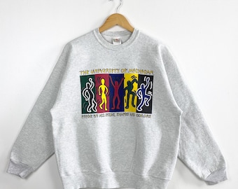 May include: A light grey sweatshirt featuring the text "THE UNIVERSITY OF MICHIGAN" above a colourful graphic of stick figures. The graphic is in a rectangular shape with the words "PRIDE IN ALL SIZES, SHAPES AND COLORS" below it.