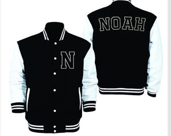 May include: A black and white varsity jacket featuring the name "NOAH" on the back and the letter "N" on the front. The jacket has white sleeves, a black body, and striped detailing on the collar, cuffs, and hem.