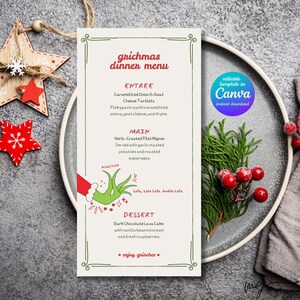 Puede incluir: Una tarjeta de menú de cena navideña con un borde verde, que presenta opciones de entrantes, plato principal y postre. La tarjeta está sobre un plato gris con vegetación y bayas rojas, con un adorno de estrella y copo de nieve de madera.