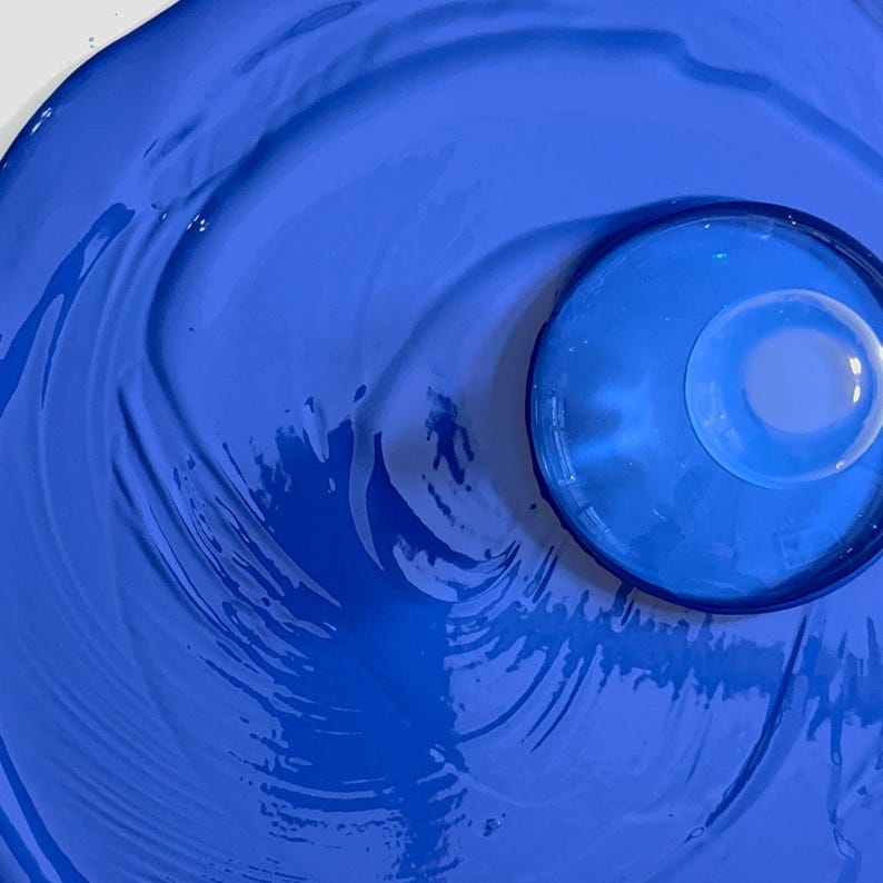 Close-up of smooth lapis lazuli ultramarine blue gouache paint with creamy circular texture with a glass muller after milling.
