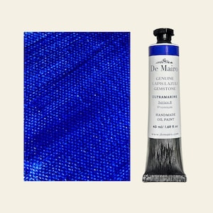 May include: A tube of De Mairo Ultramarine Series 8 handmade oil paint, 1.69 fl oz, next to a textured blue surface. The tube has a black cap and a label with the text "GENUINE LAPIS LAZULI GEMSTONE".