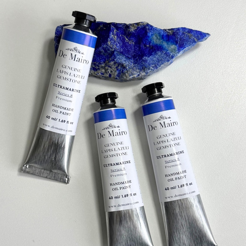 May include: Three tubes of De Mairo handmade oil paint, labeled "Genuine Lapis Lazuli Gemstone Ultramarine." Each tube is 40 ml / 1.69 fl oz. A piece of raw lapis lazuli gemstone is in the background.