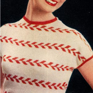 Può includere: Un top in maglia bianco in stile vintage con motivi e finiture rosse a forma di foglia. Il top a maniche corte ha uno scollo tondo ed è indossato da una persona con capelli biondi e rossetto rosso. Il testo "Maison Lily Design" è visibile.
