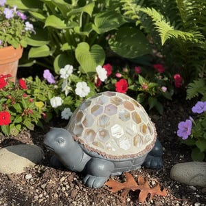 May include: A gray turtle garden statue featuring a shell decorated with a mosaic of hexagonal, iridescent, cream-colored shell tiles. The turtle has a smooth, matte gray finish on its head, legs, and tail, contrasting with the textured shell.