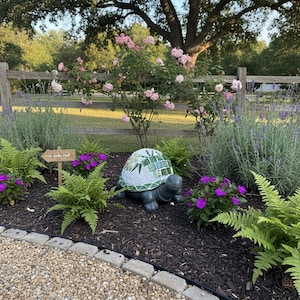 Estatua de tortuga hecha a mano y elaborada artesanalmente decorada con azulejos de cerámica y vidrio que muestra flores en una maceta verde.