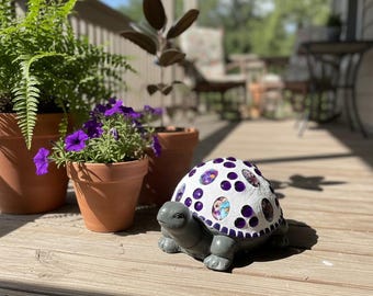 Estatua de tortuga para jardín, hecha a mano y decorada con gemas ovaladas de vidrio en forma de flores moradas y azules, y mosaicos cuadrados de cerámica morada.