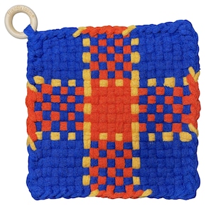 May include: A square, woven hot pad in blue, orange, and yellow. The design features a cross shape in orange and yellow against a blue background. A wooden ring is attached for hanging. The text "friendly loom" is printed on the ring.