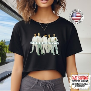 May include: Black crop top featuring a graphic of the band members of Millennium in white outfits. The word "Millennium" is displayed in a silver font. A "Made in the USA" sticker is visible.