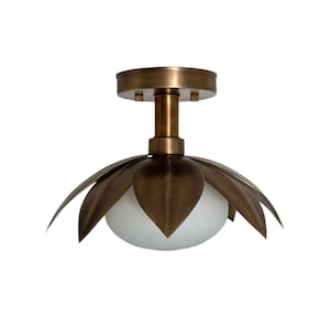 Op de afbeelding: Een bronzen plafondlamp met een bloemmotief. De lamp heeft een centraal bolvormig licht omgeven door bloemblad-vormige elementen. De lamp is gemonteerd op een cirkelvormige basis.