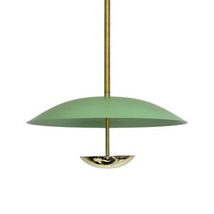 May include: A modern pendant light fixture with a mint green shade and a brass-colored stem and decorative element. The shade is a wide, shallow dome shape. The fixture hangs from a brass-colored rod.