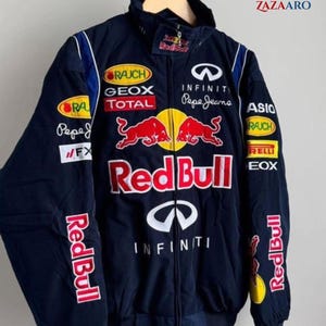 Puede incluir: Chaqueta azul marino con cremallera y múltiples logotipos de patrocinadores, incluyendo "Red Bull", "Infiniti" y "Pepe Jeans". La chaqueta presenta un cuello alto y un prominente logotipo de Red Bull en el pecho. Las mangas también muestran el logotipo "Red Bull".