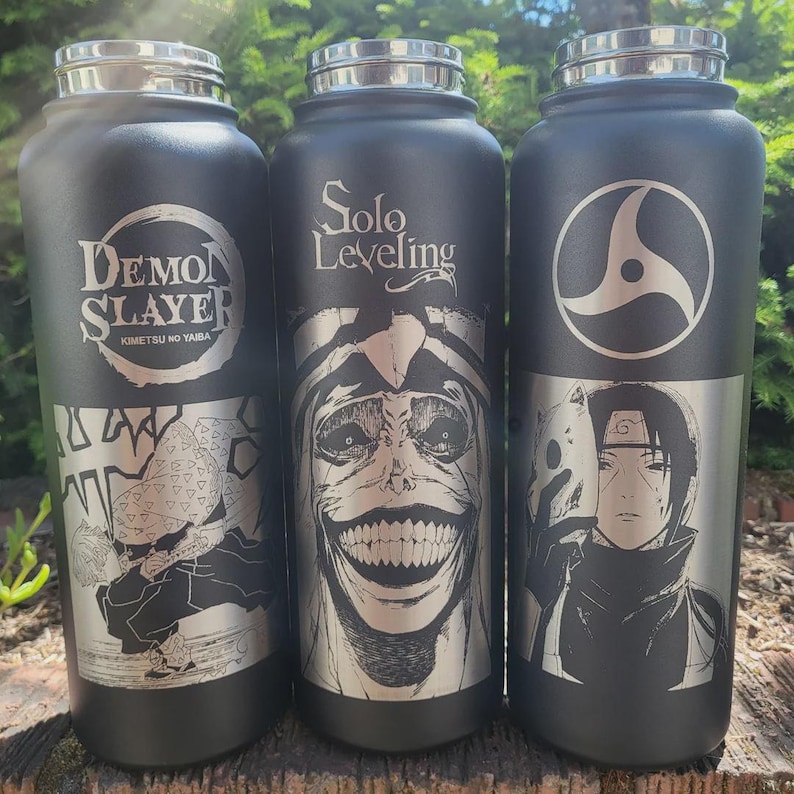 Pode incluir: Tr&ecirc;s garrafas de &aacute;gua isoladas pretas com tampas prateadas. Cada garrafa apresenta um design diferente com tema de anime: "Demon Slayer", "Solo Leveling" e um personagem com uma m&aacute;scara. As garrafas s&atilde;o cil&iacute;ndricas e parecem ser de a&ccedil;o inoxid&aacute;vel.