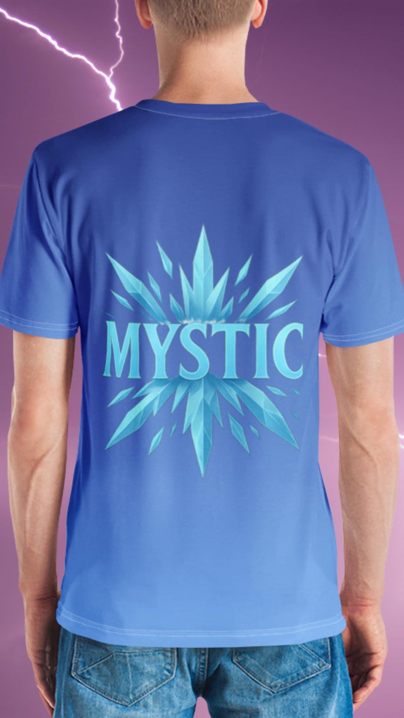 K&ouml;nnte beinhalten: Blaues T-Shirt mit Farbverlauf. Auf der R&uuml;ckseite des Shirts steht das Wort "MYSTIC" in Hellblau, umgeben von einem stilisierten, eisigen Kristall-Design. Das Shirt hat kurze &Auml;rmel.