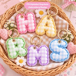 Puede incluir: Cinco llaveros de alfabeto acolchados con borde festoneado y patrón de cuadros vichy en rosa, amarillo, verde, morado y azul. Cada letra está unida a una anilla de metal dorado. El texto ITH Alphabet Keychain Embroidery Design es visible.