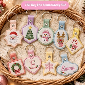 Puede incluir: Una colección de diez llaveros ITH Key Fob Embroidery File en varias formas, incluyendo estrellas, corazones, círculos y nubes. Cada uno presenta bordados navideños como Santa, un árbol, un muñeco de nieve, un reno y el nombre Emma.