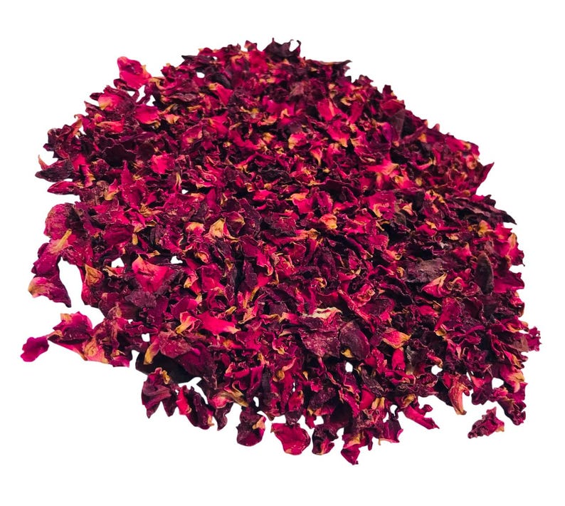 May include: A pile of dried rose petals in shades of deep red and burgundy, with hints of yellow. The petals are irregularly shaped and appear to be slightly curled, creating a textured appearance. The background is plain white.