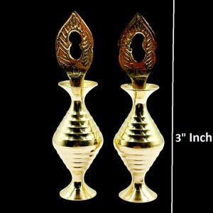 Puede incluir: Dos frascos de delineador de ojos dorados y ornamentados, cada uno con una tapa decorativa. Las botellas miden aproximadamente 7,6 cm de alto. Se muestra el texto "Buy 1 Get 1 Free" y "Black Eyeliners Free".