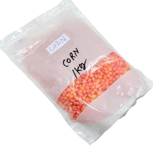 Könnte beinhalten: Ein durchsichtiger Plastikbeutel gefüllt mit orangefarbenen und gelben Maiskörnern. Der Beutel hat ein weißes Etikett mit "CORN" und ein handgeschriebenes Etikett mit "CORN / 1Kg". Der Beutel ist versiegelt.
