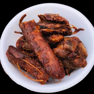 Può includere: Una ciotola bianca piena di tamarindo. Il tamarindo è di colore marrone scuro con una consistenza leggermente appiccicosa. Il frutto ha un sapore agrodolce ed è spesso usato nella cucina asiatica.