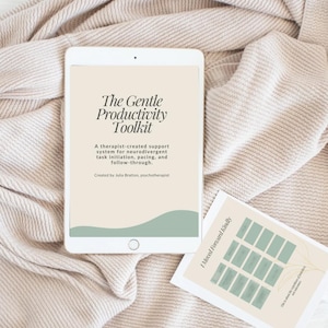 May include: A white tablet displays "The Gentle Productivity Toolkit" with text describing a support system for neurodivergent individuals. A small card with a green and beige design is also present, all on a beige fabric.