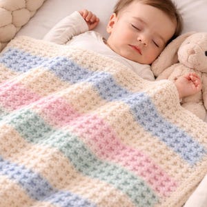 May include: A sleeping baby is nestled in a crib, covered by a soft, pastel-striped blanket. The blanket features alternating bands of cream, pink, blue, and green. A plush bunny toy rests beside the baby, adding a touch of comfort.