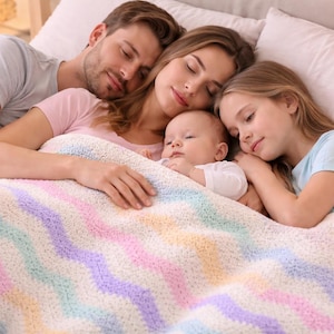 May include: A family of four asleep in bed, under a pastel-coloured blanket. The blanket features a wavy pattern in white, pink, blue, and yellow. The family consists of a man, a woman, a baby, and a young girl.
