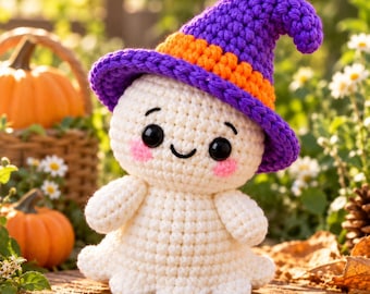 Puede incluir: Una figura de fantasma tejida a ganchillo en color blanco con un sombrero de bruja morado y una banda naranja. El fantasma tiene ojos negros, una sonrisa bordada en negro y mejillas rosadas. La figura presenta un patrón de punto texturizado.