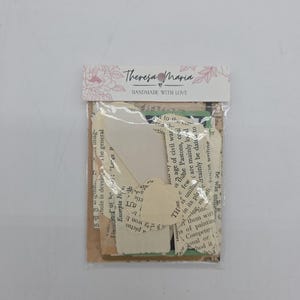 May include: A clear plastic bag containing a collection of torn paper ephemera. The paper pieces include text from books and other printed materials. The bag has a label with the text "Theresa Maria Handmade with Love".