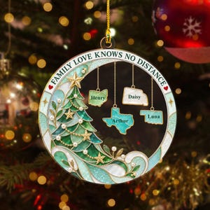 May include: A circular Christmas ornament featuring a stained-glass style green tree with gold stars and white pearls. The text FAMILY LOVE KNOWS NO DISTANCE is printed on the frame. Four state-shaped charms hang inside, labelled Henry, Daisy, Arthur, and Luna.