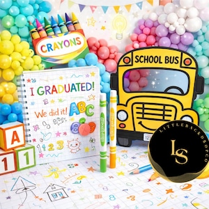 May include: A vibrant school-themed backdrop with a yellow school bus cutout, a box of crayons, and a notebook with the text "I GRADUATED!". Balloons in various colours and wooden blocks with numbers and letters complete the scene.