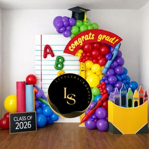 Könnte beinhalten: Ein farbenfroher Hintergrund zum Thema Abschlussfeier mit Luftballons, einem Doktorhut und den Worten "congrats grad!" Eine Tafel zeigt "Class of 2026". Der Hintergrund umfasst ein großes Notizbuch, Buntstifte und die Buchstaben A und B.