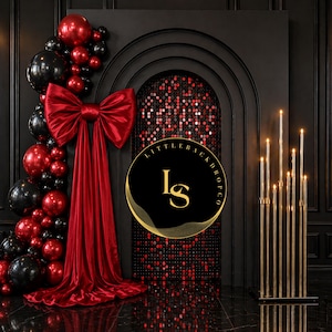 May include: A black backdrop with a red and black balloon arch, a large red bow, and a gold candle display. The backdrop features a sequined archway and a logo that reads "Little Backdrop Co."