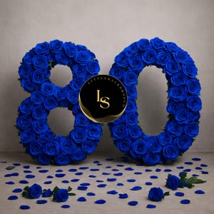 Peut inclure: Une composition florale en forme du chiffre 80, faite de roses bleu vif. Des pétales de roses bleues et des roses individuelles sont dispersés à la base. Un logo noir et or est au centre.