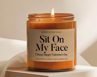May include: An orange candle in a clear glass jar with a lit wick. The label reads "Sit On My Face, I Mean, Happy Valentine's Day." The candle is hand-poured and made of 100% soy wax, with a net weight of 255g.