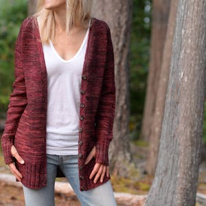 May include: A maroon cardigan with a V-neck and button closure. The cardigan has a speckled pattern and is made of a soft, knit fabric.